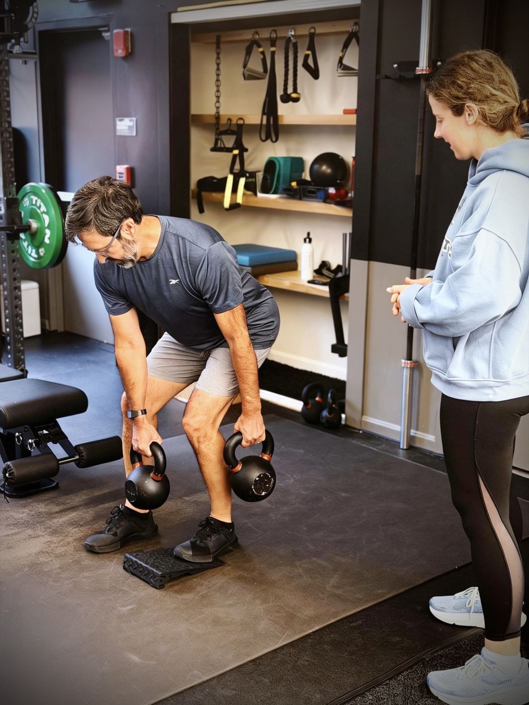 A trainer coaching a client through a kettlebell deadlift