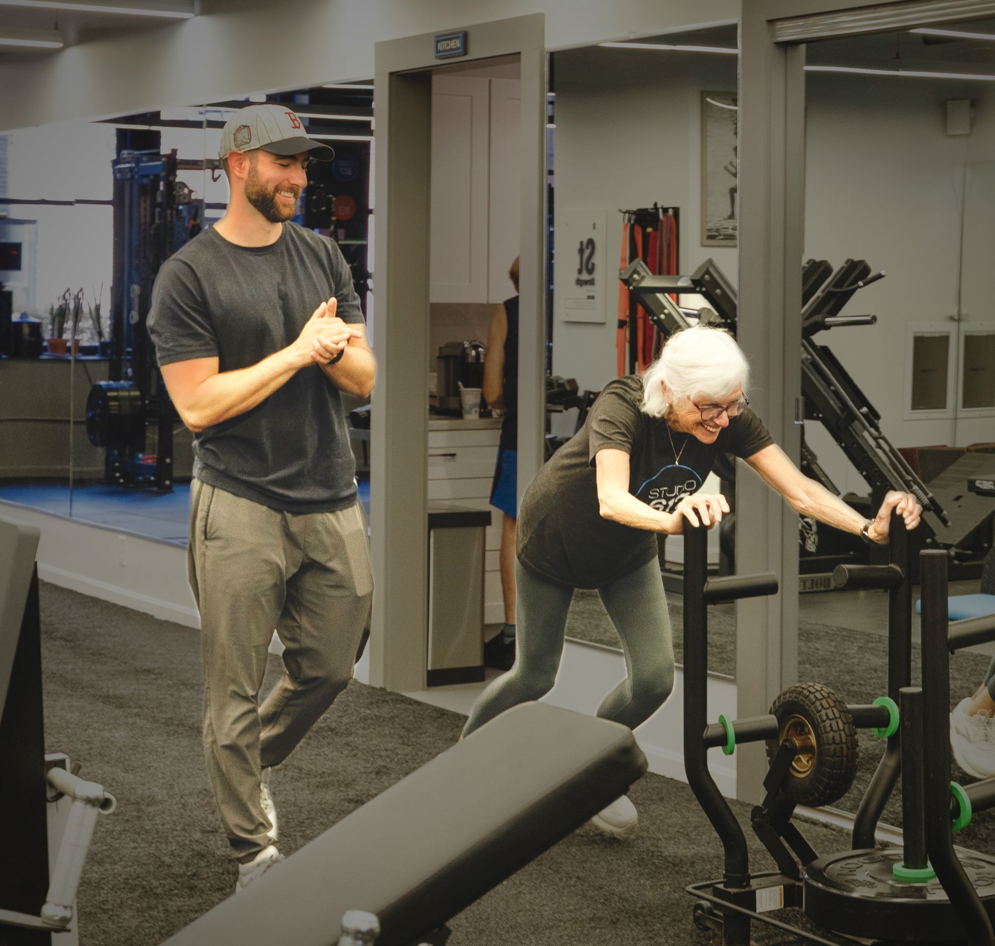A Studio 617 trainer cheering on a client as she pushes the sled