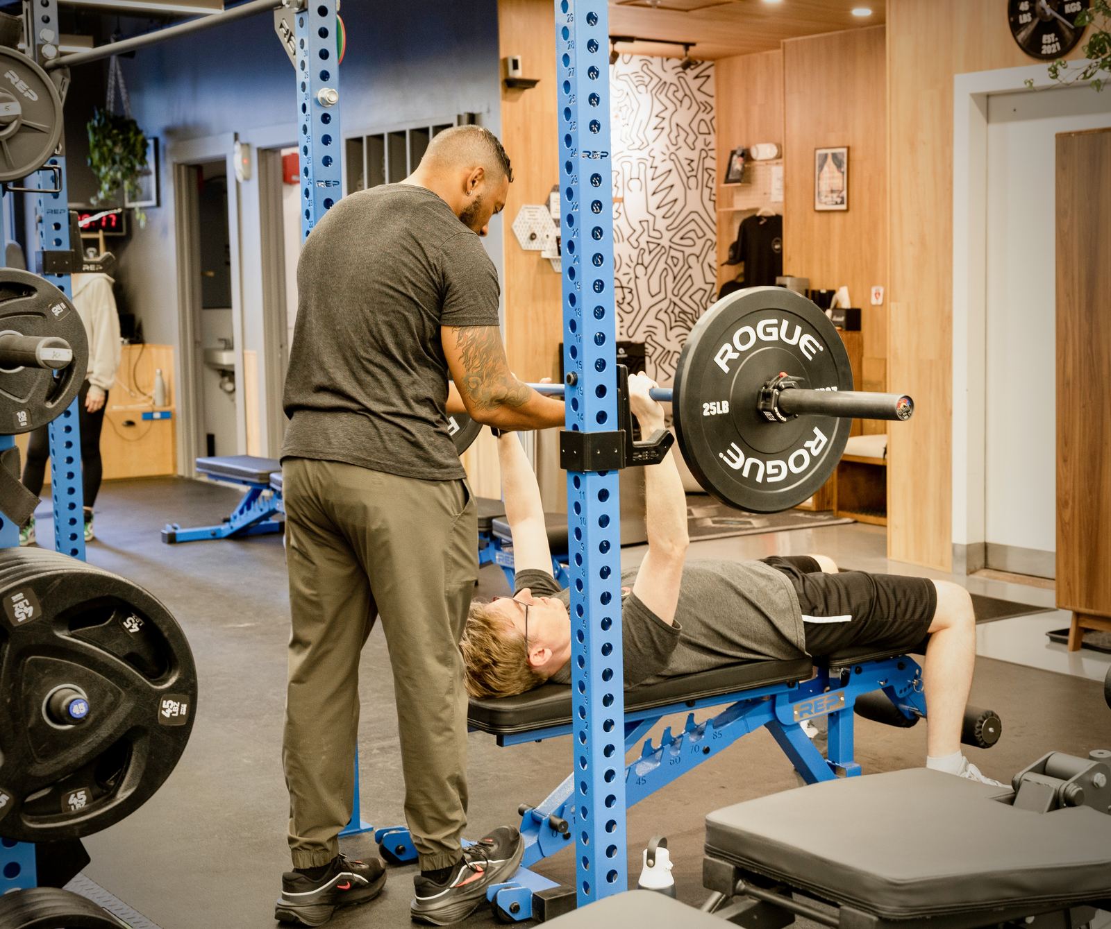 A trainer spotting a client on the bench press